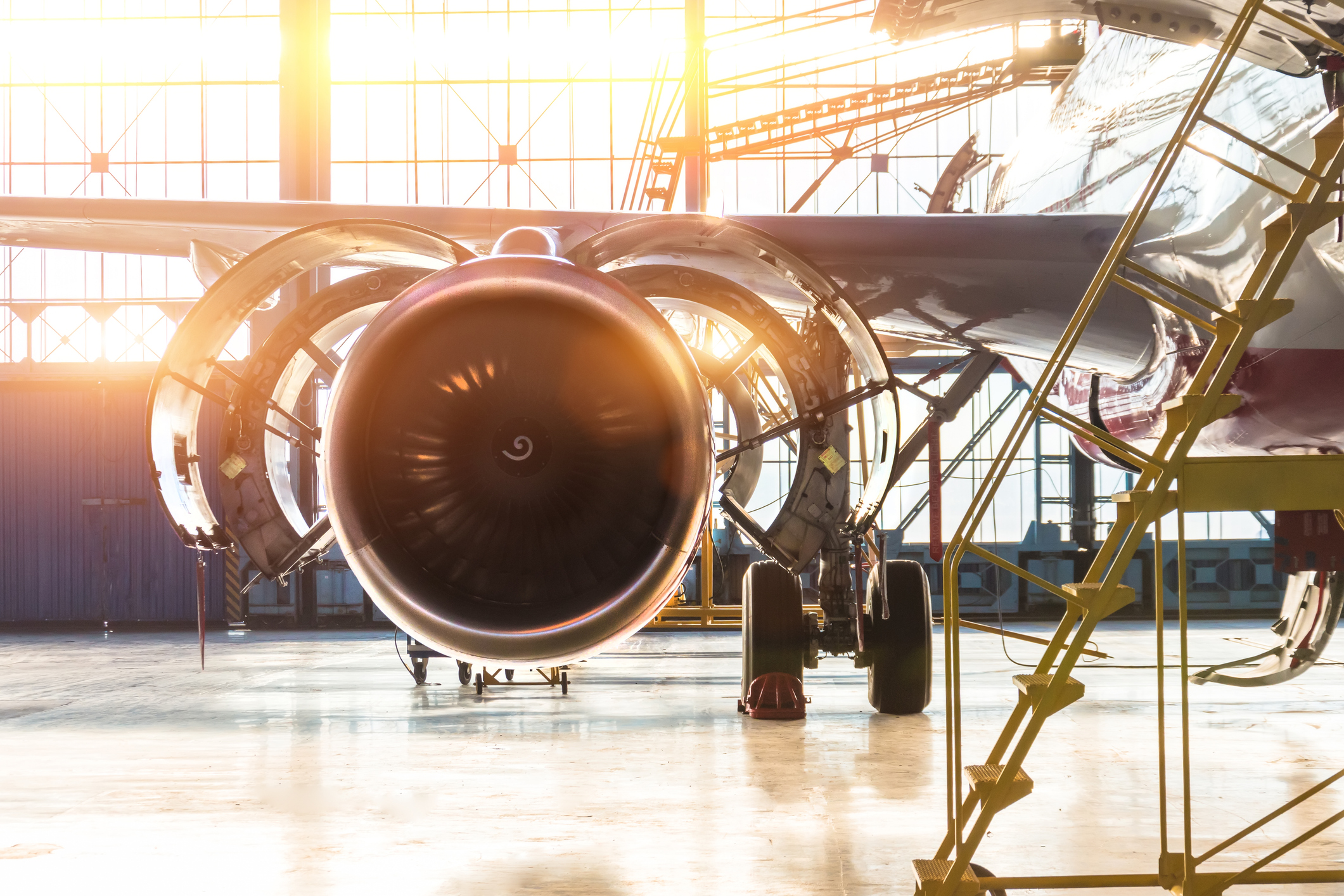 Opened hood airplane engine jet maintenance in the hangar stairs ,with bright light flare at the gate.